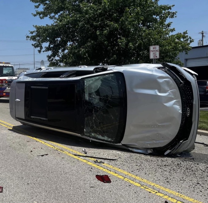 An overturned silver SUV on a road.