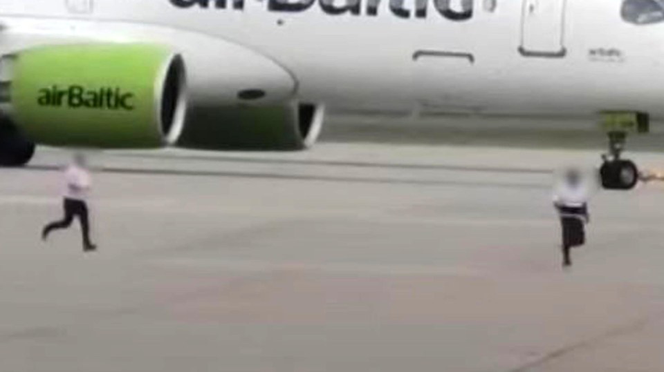 A man is chased on an airport tarmac near an airBaltic plane.