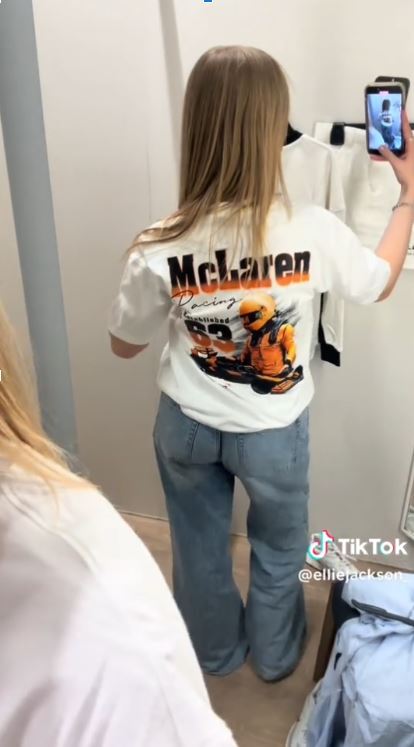Woman trying on a McLaren racing-themed t-shirt.