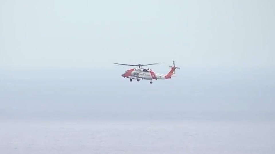 Coast Guard helicopter in flight over water.