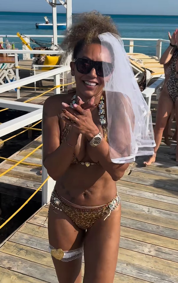 Woman in a leopard-print bikini and veil on a dock.