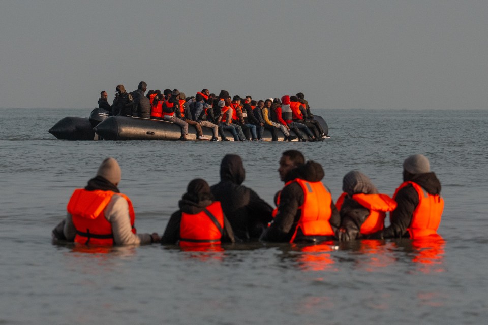 Migrants in a small boat and in the water.