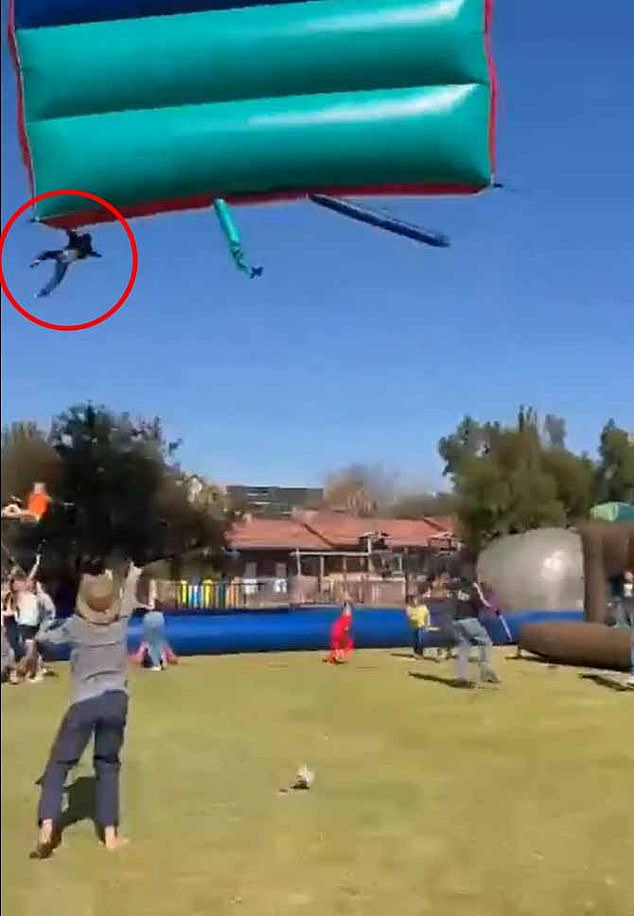 Terrifying footage captures the moment two school children cheat death after falling from a bouncy castle blown 40 feet into the air by high winds