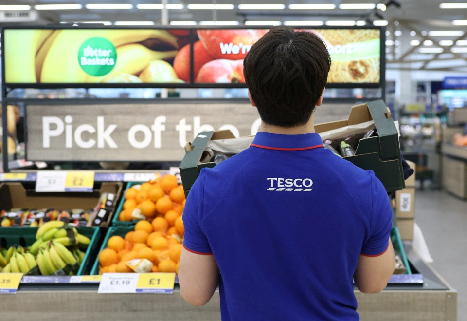 Tesco employee restocking produce.
