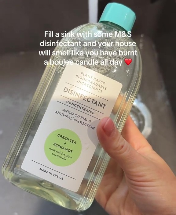 A hand holding a bottle of M&S disinfectant.