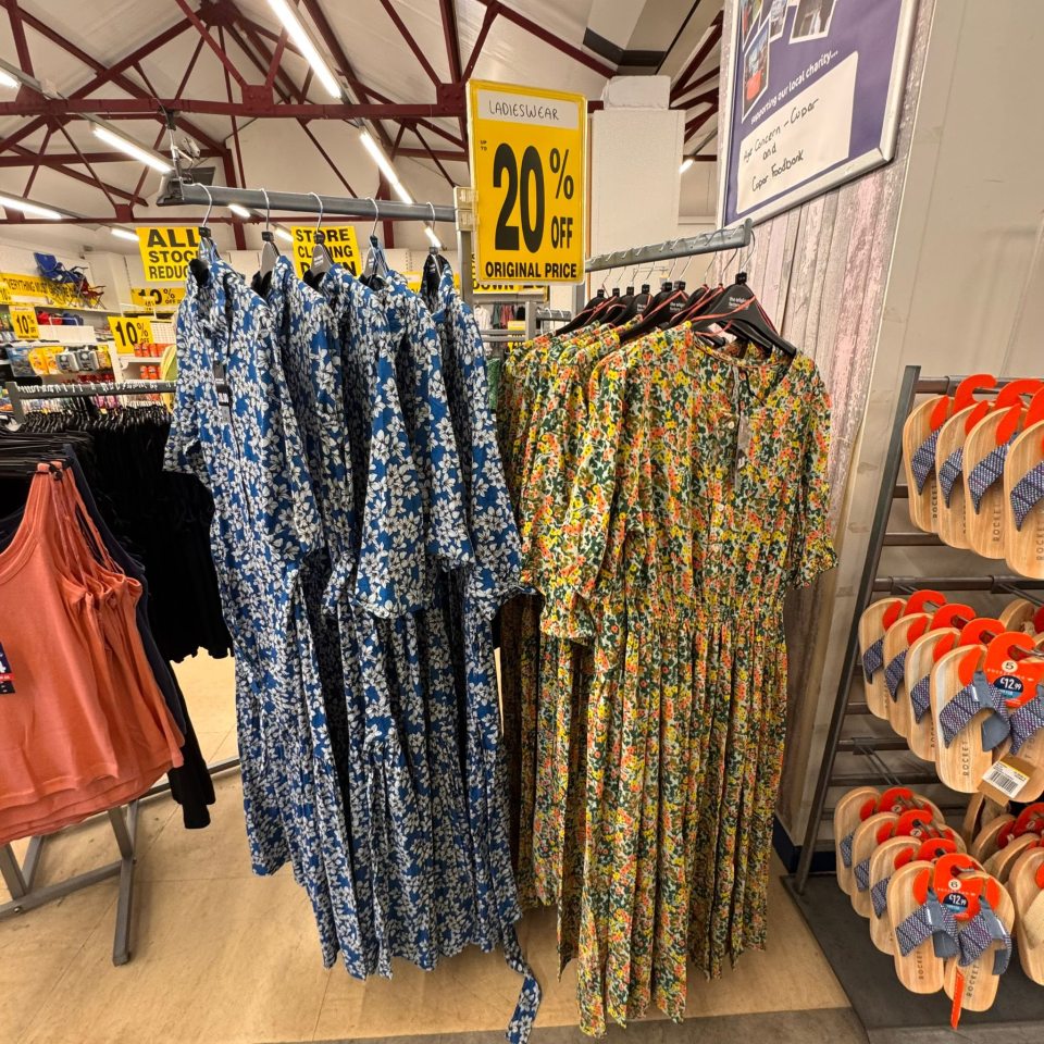 Floral dresses on display in a closing down shop sale.