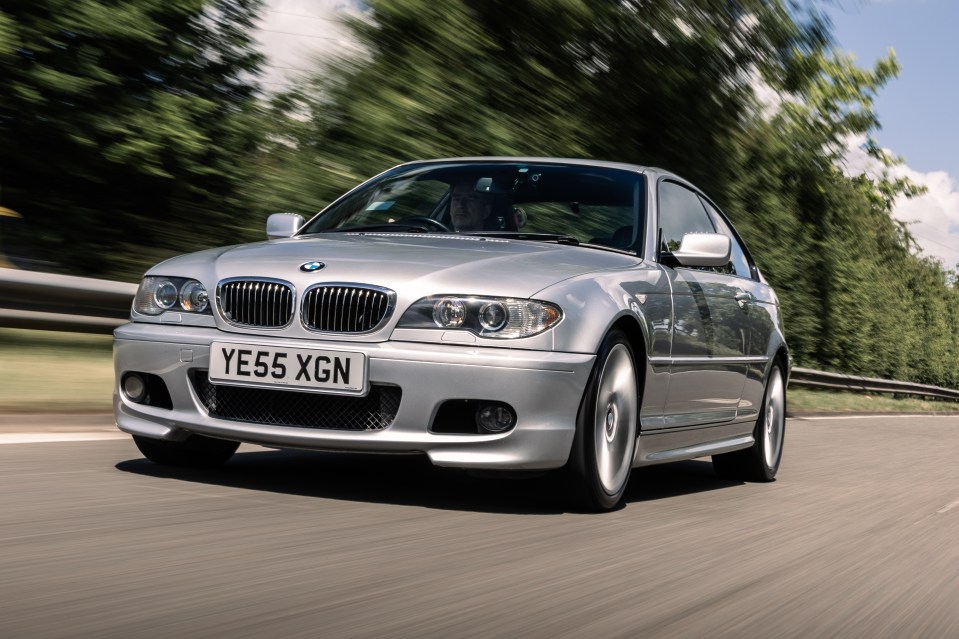 Silver BMW driving on a road.