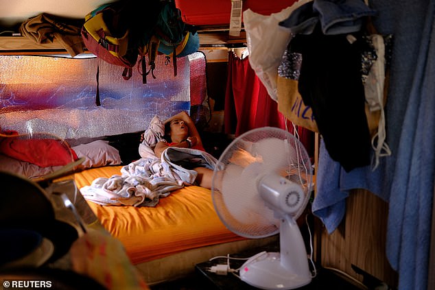 An army of homeless Ibiza workers are being forced to sleep in makeshift camps after being priced out of homes by soaring rent prices. Pictured: Rocio sleeps inside her motorhome, as her father sits outside