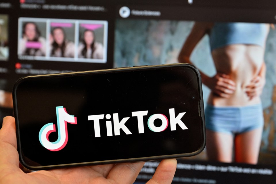 TikTok logo on a smartphone with a blurry background image of a thin woman.