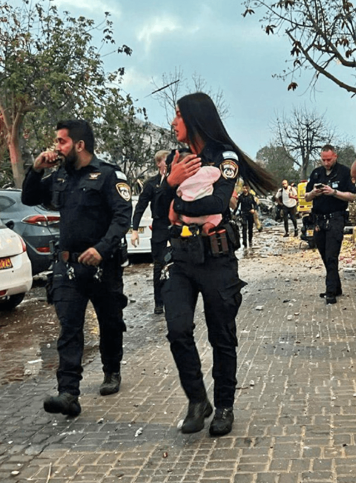 A police officer carrying a baby rescued from rubble after an Iranian missile strike.