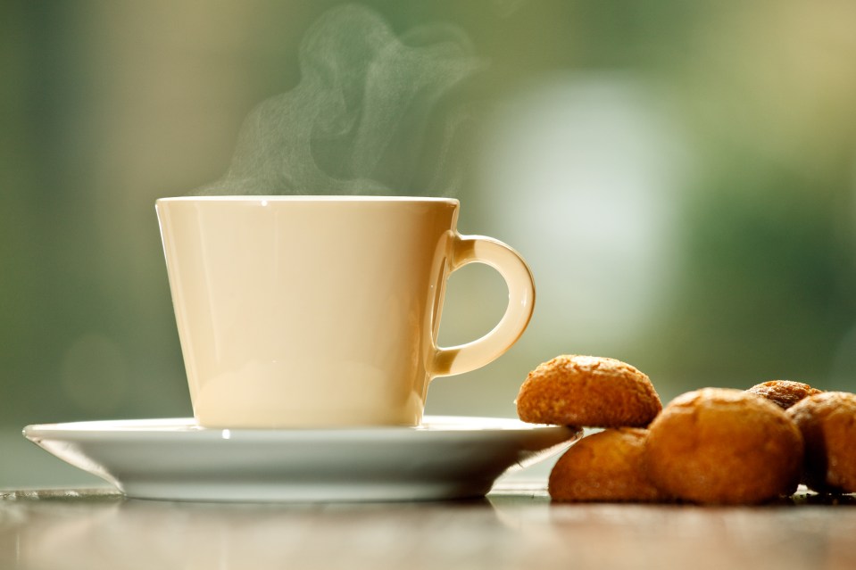 A steaming cup of coffee with cookies on a saucer.