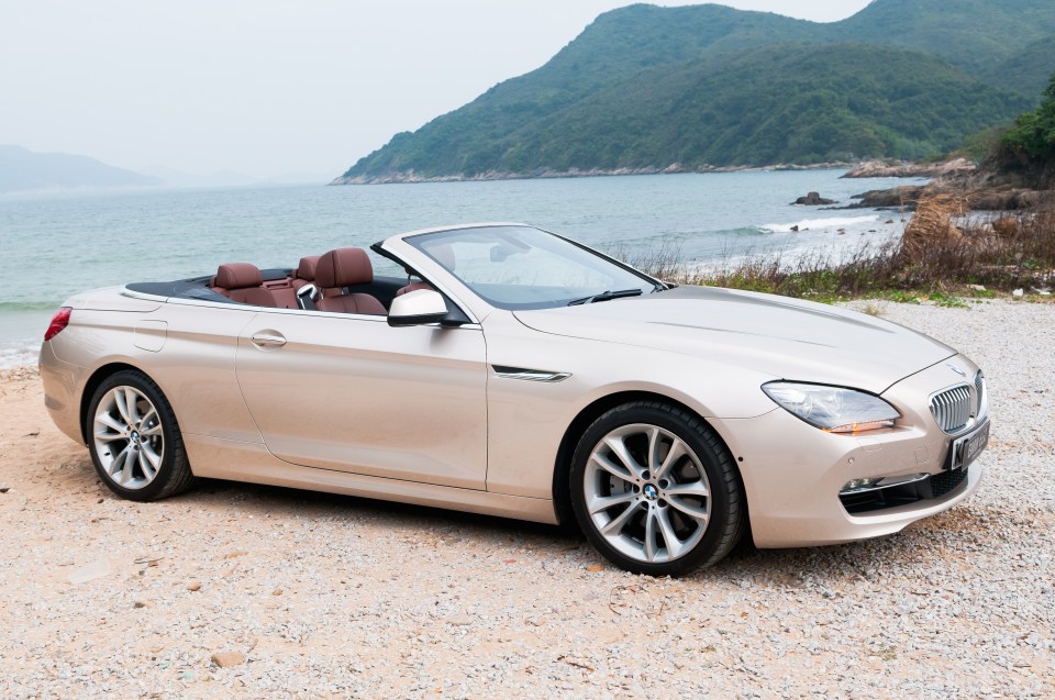 Beige BMW 6-series convertible parked by the ocean.