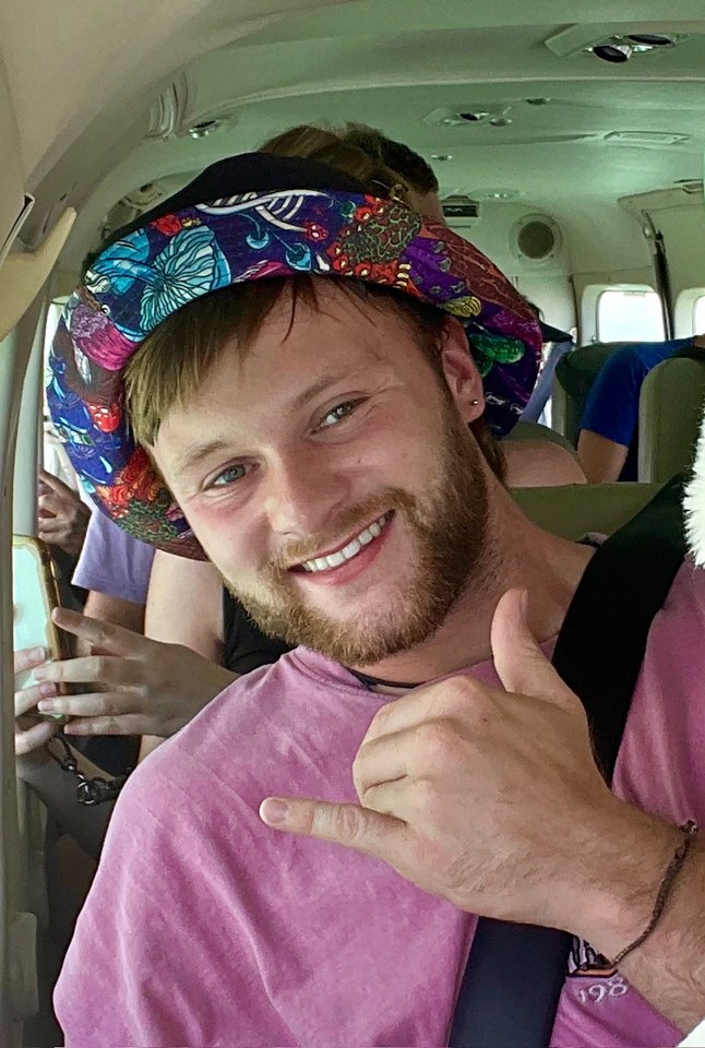 Photo of Sam Gardiner, wearing a patterned hat, giving a shaka sign.