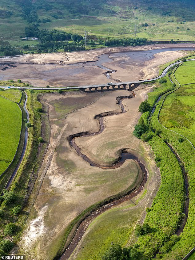 A drone view shows vehicles using a bridge to pass over a dry section of the Woodhead Reservoir after a prolonged period without rain saw water levels