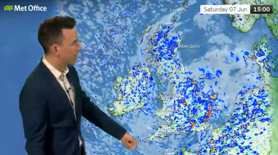 Weather presenter pointing at a weather map of the British Isles showing rain.