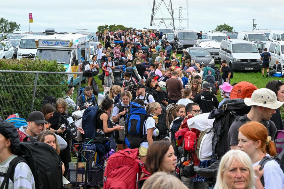 Large crowd of people waiting in line with backpacks at the Glastonbury Festival.