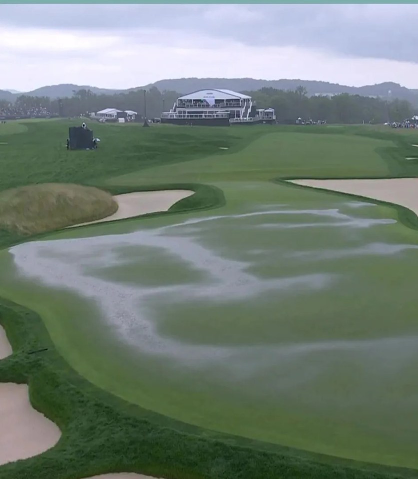 Golf course and golfers under umbrellas during a rain delay.
