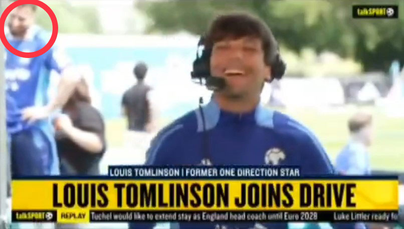 Louis Tomlinson smiling into a microphone during a Soccer Aid interview.