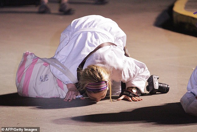 Kendall Jenkins, a passenger on the infamous 'poop cruise,' kisses the ground after the the stricken cruise was towed into Mobile, Alabama, on February 14, 2013