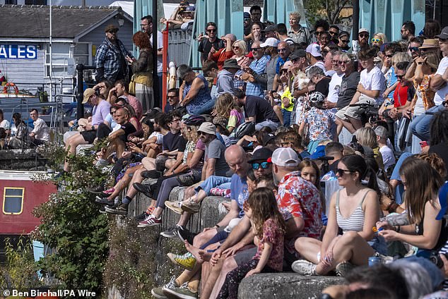 Sunbathers pictured sitting on a wall at Bristol Harbourside on Sunday. Parts of the UK will bask in 24C heat today as the balmy summer conditions continue