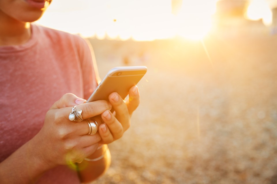 Close-up of a woman using a smartphone at sunset.