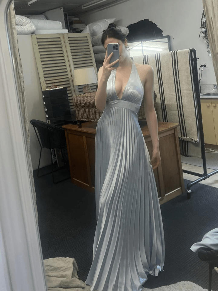Woman in a light blue pleated maxi dress taking a selfie.