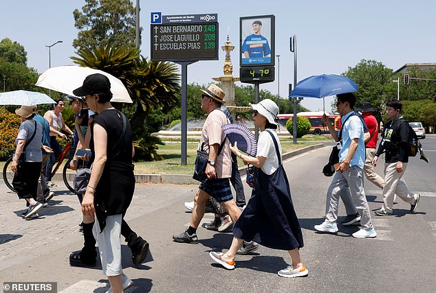 Pictured: People use umbrellas and a hand fan next to a thermometer displaying 47C during a heatwave in Seville, Spain, July 1, 2025