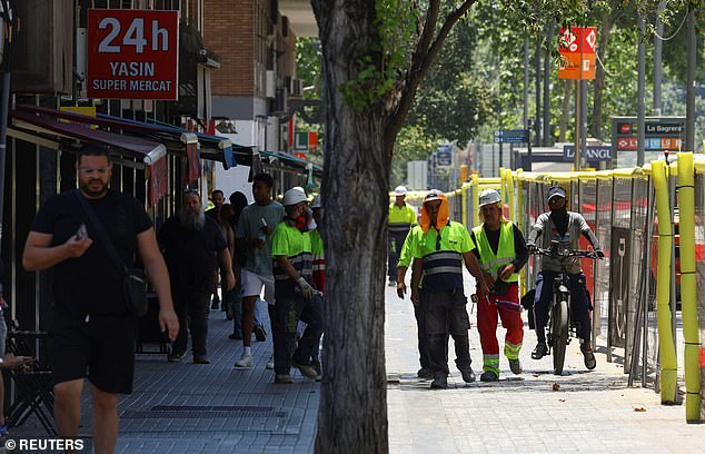 Pictured: Workers walk under the sun during a heatwave in Barcelona, Spain, July 1, 2025