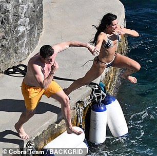 The pair were seen playfully jumping hand-in-hand into the sea