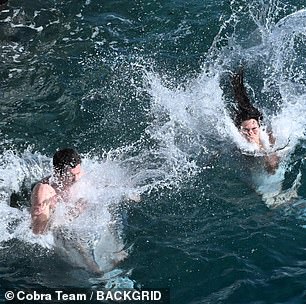 The pair were seen playfully jumping hand-in-hand into the sea