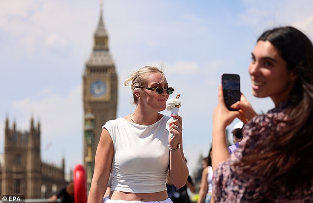A woman eats an ice cream while walking over Westminster Bridge in London on Tuesday afternoon