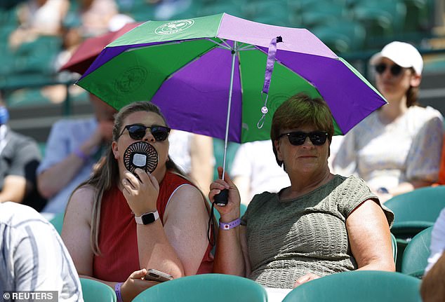Spectators in the Wimbledon stands use fans to cool down and umbrellas to take cover yesterday