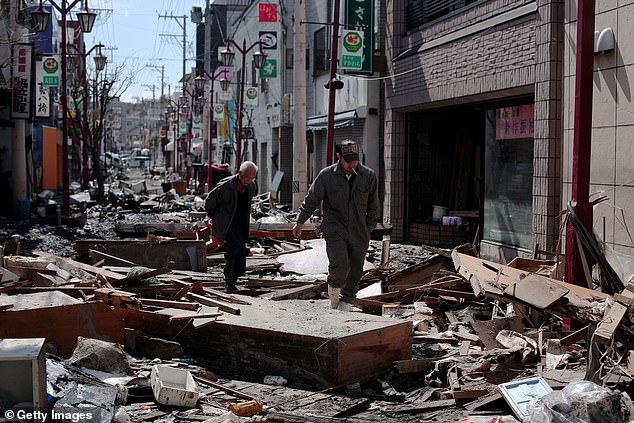Two men walk through the rubble and debris on March 18, 2011 in Ishinomaki, Japan after a quake triggered a tsunami wave which engulfed large parts of north-eastern Japan