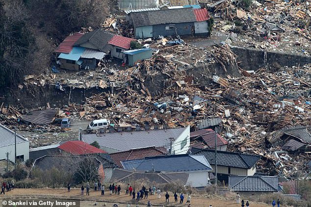 In this aerial image, people look at destroyed houses on March 12, 2011 in Minamisanriku, Miyagi, Japan
