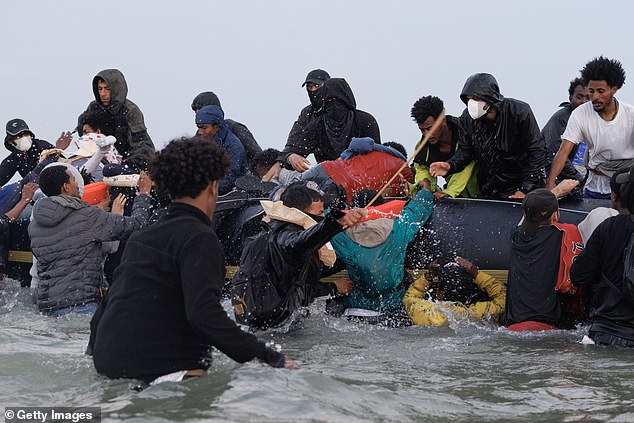 Cane poised, an alleged trafficker tried to manage the scene as the desperate migrants heaved themselves onboard while one seems to have slipped under