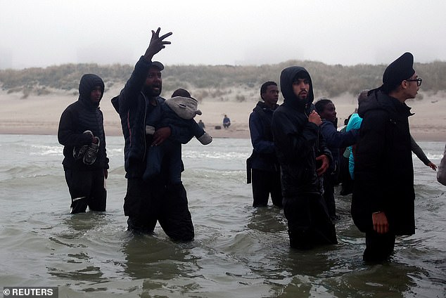 A man carrying a baby gestures towards the boat that would have taken them across the Channel