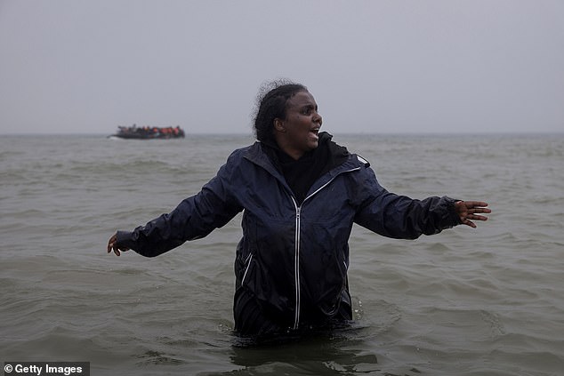 A distraught woman is devastated at not being able to get a place on the crowded small boat seen sailing in the background