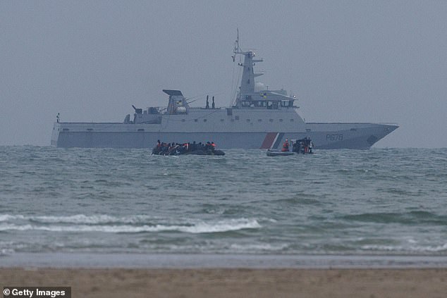 The frenzy to get out of the water and sail to the UK was in vain as minutes later the crowded boat was intercepted by French cops (a French war ship is seen in the background)