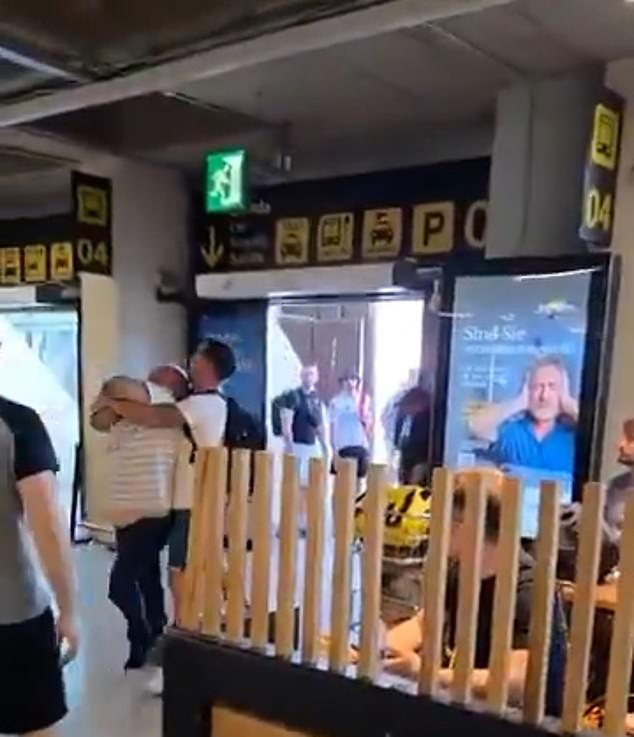 One of the men falls onto his knees before a bystander steps in and tries to restrain the other in a bear hug as he fights to escape the clinch