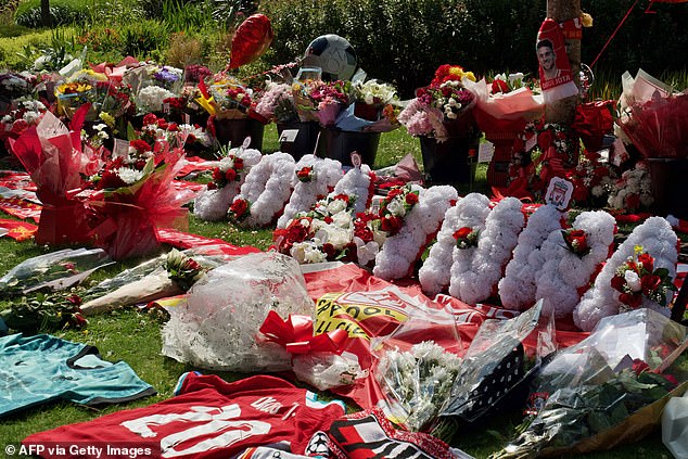 Liverpool shirts and scarves are seen beside flowers left at a memorial set up close to Anfield