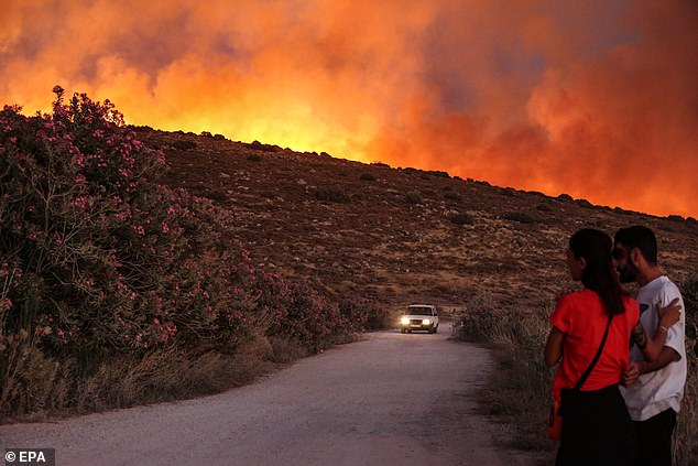 People look at a wildfire in the Cesme district of Izmir