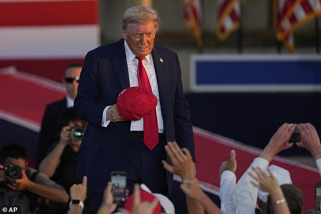 President Donald Trump takes off his signature red hat after speaking to a crowd Thursday night at the Iowa State Fairgrounds in Des Moines, Iowa. He recalled how he had promised Iowa voters he would kick off the nation's birthday events in the Hawkeye State