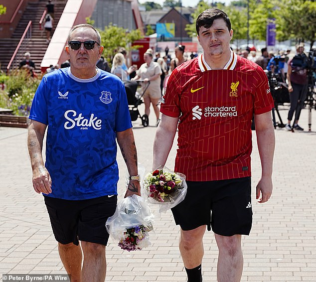 One striking image saw two men - one in a Liverpool shirt and one Everton - walk up the road carrying flowers