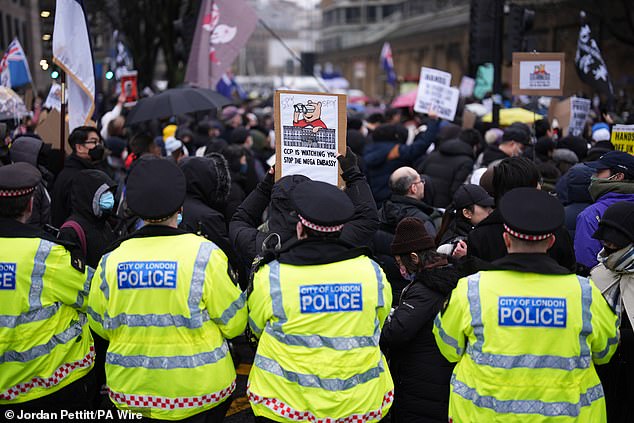 A person holds up a placard during a protest by at least 28 diasporic groups - including Hong Kong, Tibetan, Uyghur, Chinese Dissident, and other resident organisations - outside the proposed site of the new Chinese Embassy redevelopment in Royal Mint Court central London