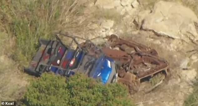 The 29-year-old's ATV is believed to have struck the bumper of a moving car and was thrown down a ravine - . Hutchins' blue Polaris ATV is seen lying on top of a rusty vehicle, which also appeared to have gone over the cliff