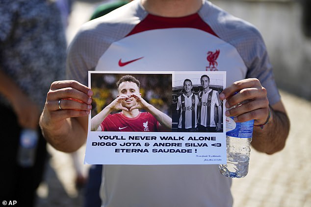 A fan wearing a Liverpool shirt holds up a a homemade message of condolence to the memory of Diogo Jota and his brother Andre