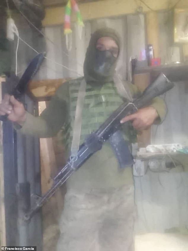 Francisco holding a military firearm and a large knife after being forcibly enlisted into the Russian military