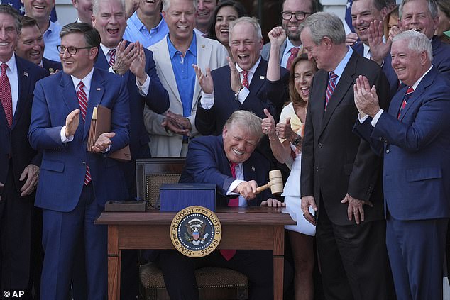 President Donald Trump bangs a gavel after signing the 'Big, Beautiful Bill' into law on Friday on the White House South Lawn as part of the annual Fourth of July celebrations. He was surrounded by GOP lawmakers including House Speaker Mike Johnson (upper left)