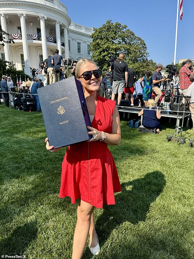 White House press secretary Karoline Leavitt holds up a copy of the 'Big, Beautiful Bill' on the White House South Lawn ahead of the president's signing of the legislation