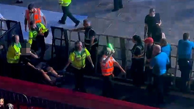 In one chaotic clip, a fan was seen holding his head as he sat on a stretcher while three emergency workers donning reflective gear surrounded him